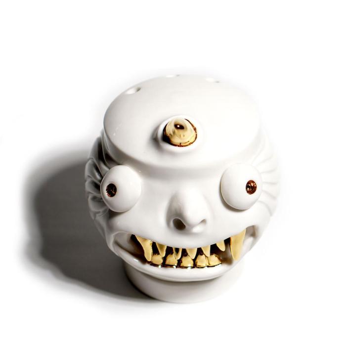 a white ceramic skull with yellow teeth and brown eyes, and a brown eyeball sticking out of the top