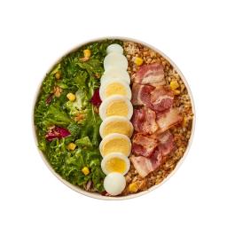 a salad with bacon, hard boiled eggs, and corn