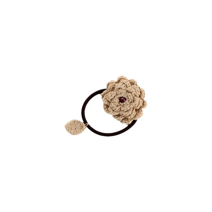 a crocheted flower and a red stone on a brown cord