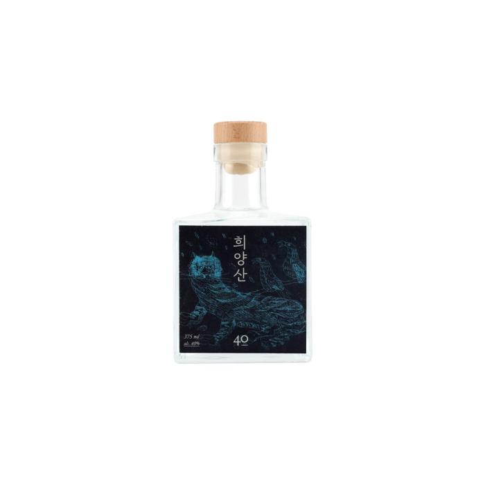 A clear square glass spirits bottle with a natural wooden cap, presented in a clean, minimalist premium style. The label is a striking dark panel with vivid blue line-art illustration and vertical Korean lettering, giving it an artisanal, contemporary edge. Its compact proportions, transparent glass, and restrained finish suggest a craft liquor or specialty soju aimed at design-conscious buyers. The overall mood is refined, modern, and gift-worthy.