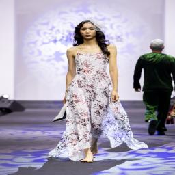 this image stands for: A model walks the runway in a white floral dress during a fashion show