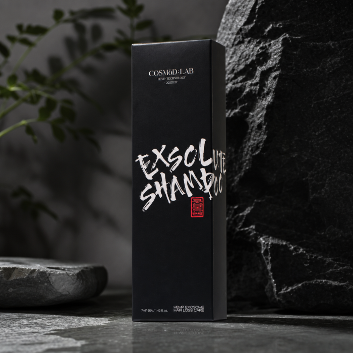 A tall, matte-black premium hair care box from COSMÖD:LAB, presented with a sleek, monolithic silhouette and understated luxury branding. The front features bold white brush-style lettering reading